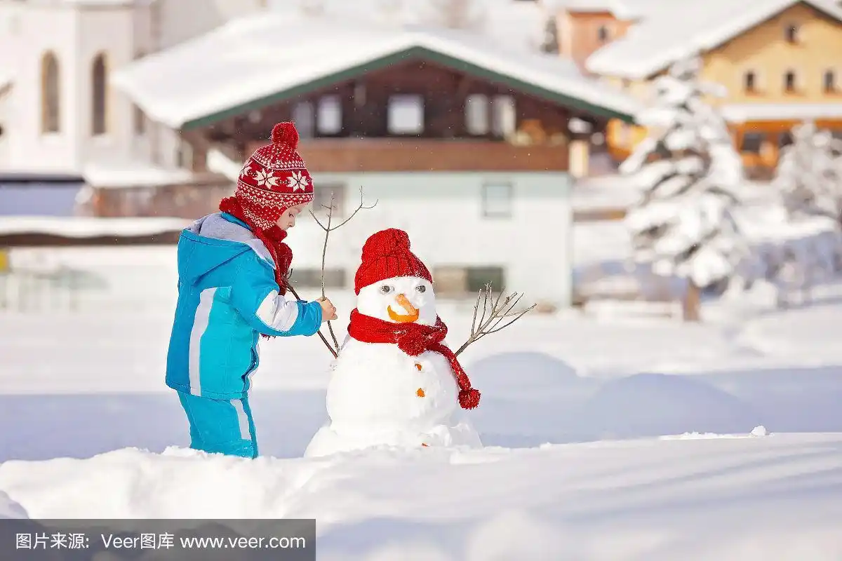 快乐美丽的孩子在花园里堆雪人,冬天