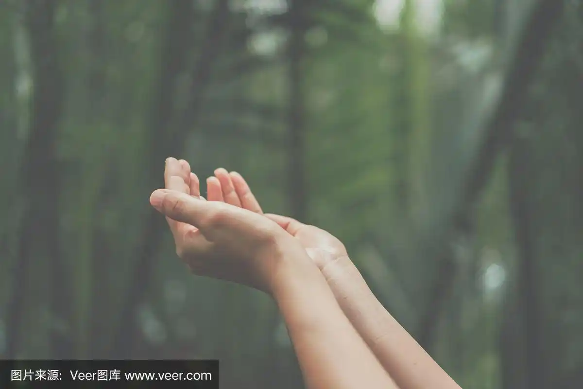 在大自然绿色的背景前,女人双手合拢像在祈祷.