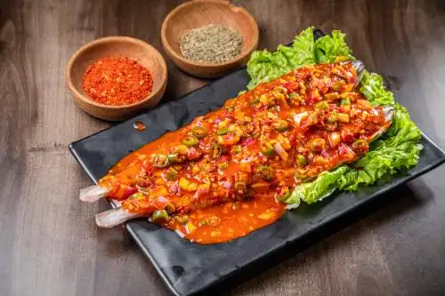 棕色木纹桌上放着一盘辣酱焖明太鱼