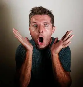 年轻的迷人和惊讶的男子的肖像在震惊和怀疑过度在惊讶的手手势在吃惊