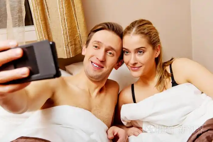 年轻夫妇躺在床上使自拍照