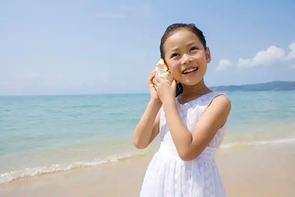 小女孩在海边听海螺