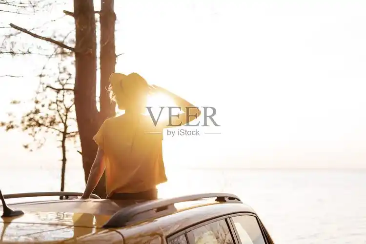 坐在车顶上欣赏日落的女人照片摄影图片