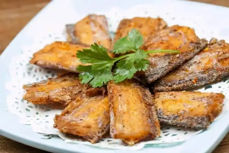 椒盐带鱼匀地挂在红薯块上,取芝麻撒在红薯上,迅速装盘,盘底事先抹上