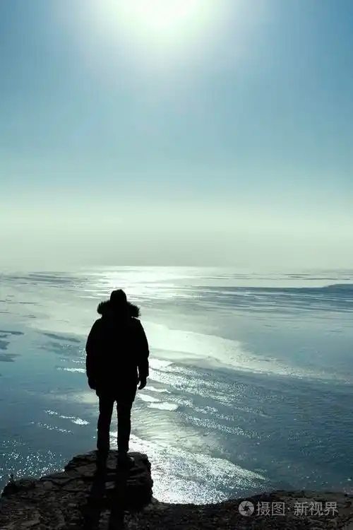 一个人的剪影留在高高的悬崖边缘冬天看太阳孤独的旅行者概念