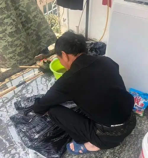 70多岁的农民工蹲在地上洗衣服