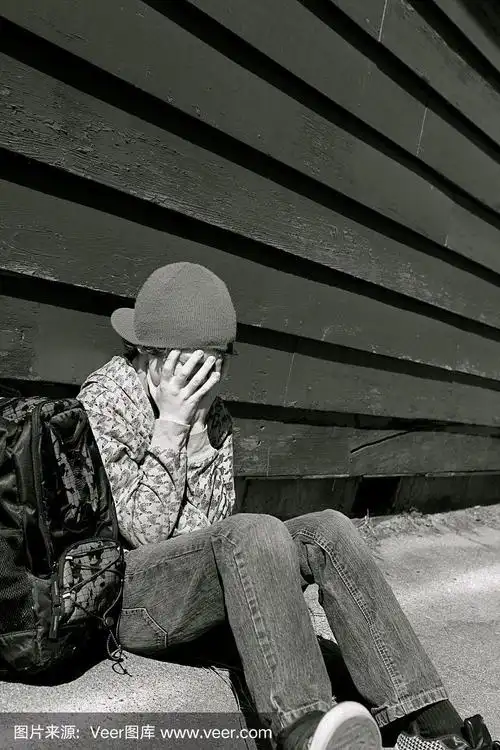 悲伤的小男孩靠在墙上