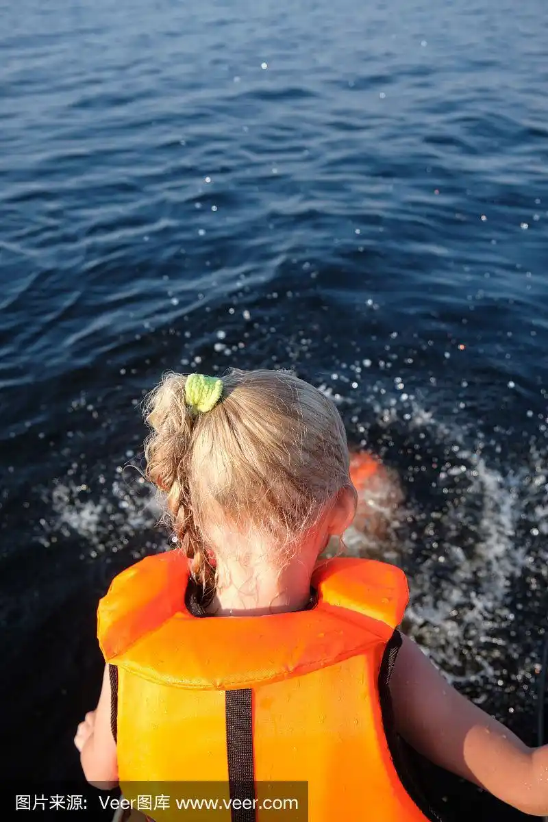 金发小女孩穿着救生衣在海里,游泳池里游泳.阳光明媚的一天.关闭了.