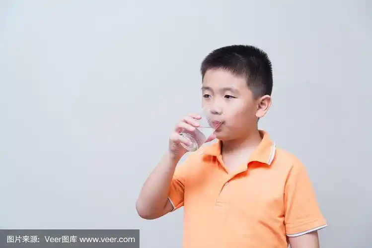 亚洲男孩从玻璃杯里喝水