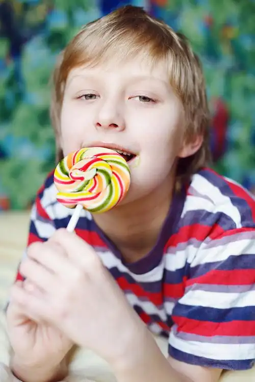 男孩吃棒棒糖,在家里吃炫彩棒棒糖的男孩