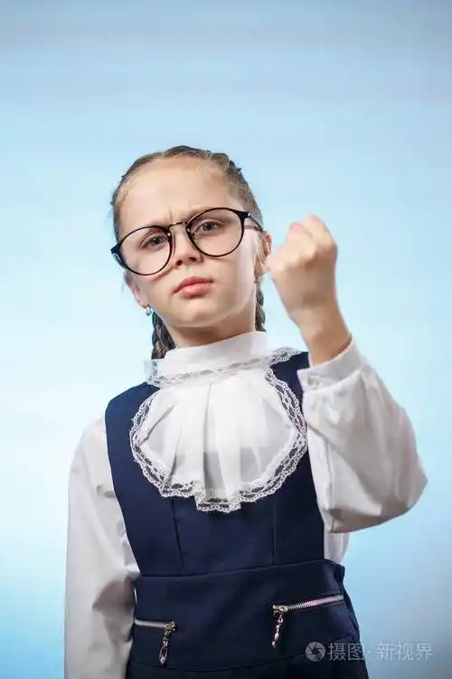 可爱的小学生做拳头蓝色背景