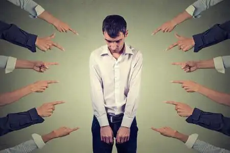 有罪的人的指控.俯视许多用手指指着他的悲伤不安的男人照片