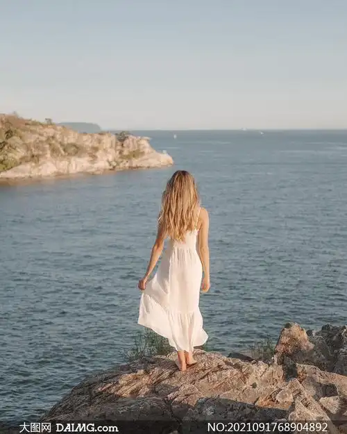 海边岩石上的白裙美女摄影高清图片