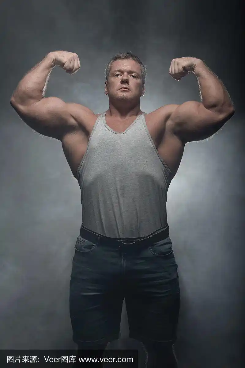 一个强壮的肌肉健美者在一个黑色的背景摆姿势.力量和健康的概念