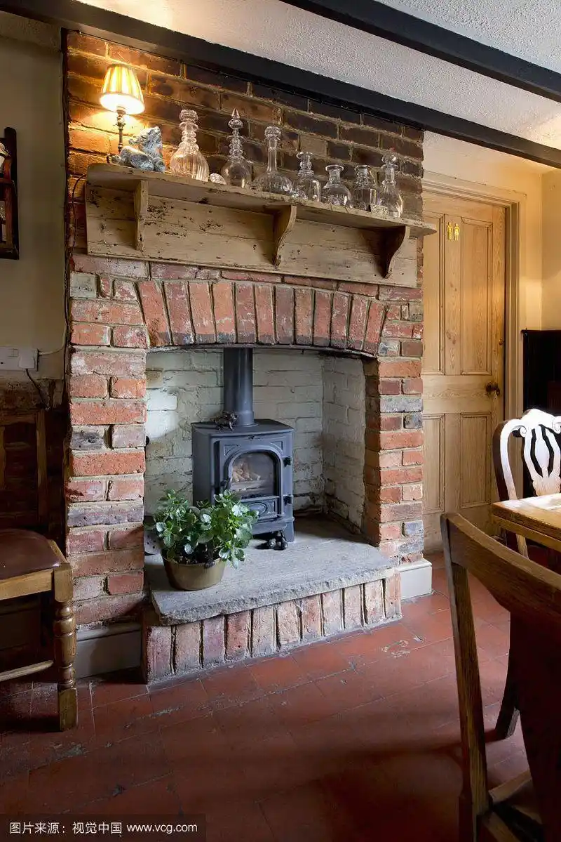 传统的砖砌壁炉里的原木燃烧炉,在乡村架子上的玻璃水瓶下面