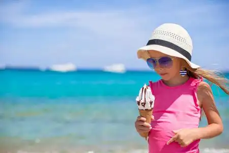 在地处热带的海滩上吃冰淇淋的小可爱女孩照片