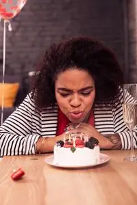 在蛋糕上吹蜡烛的漂亮快乐的女人照片