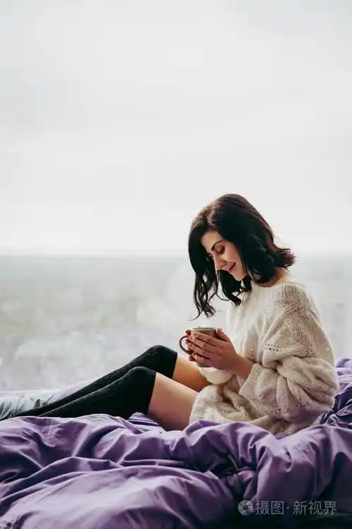 早晨,年轻的黑发女人坐在窗边喝茶