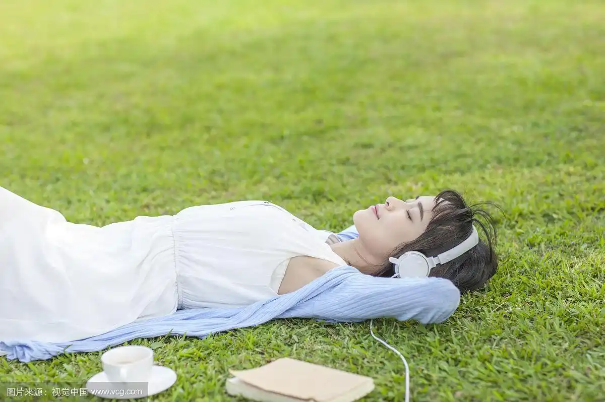 漂亮女人躺在草地上听音乐