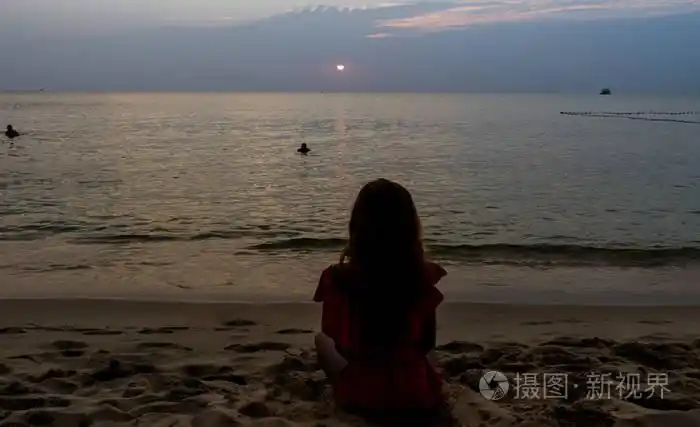 旅行女孩,留着长长的红头发,坐在海滩上,美丽的日落景色,瑜伽概念,在