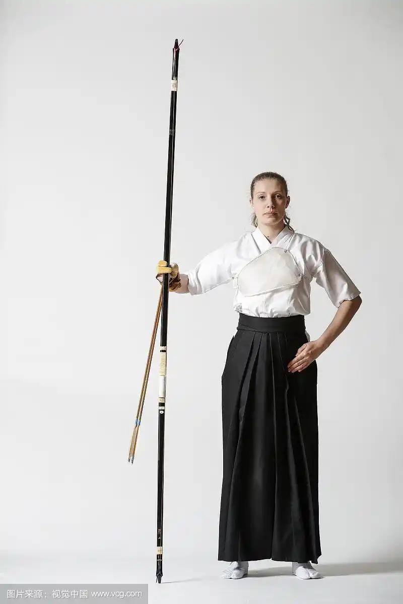 白人妇女在白色背景上练习传统日本弓道射箭