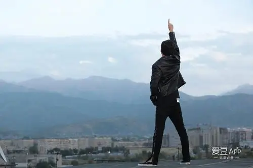 一身黑色系的酷劲背影霸气站在高处伸着右手摆出数字"1"的手势,并配文