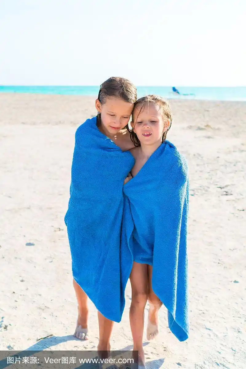 可爱的小女孩裹着毛巾在热带海滩游泳后