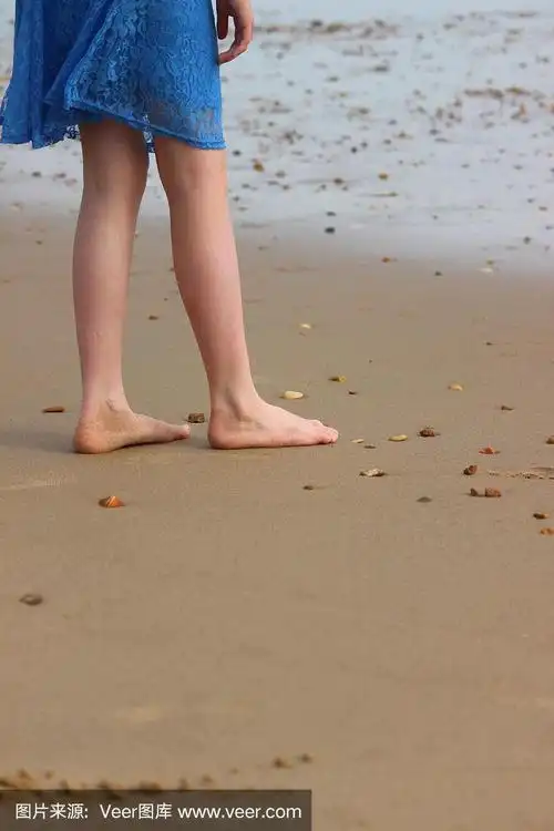 女孩赤脚走在海滩/海边的沙子,被海浪