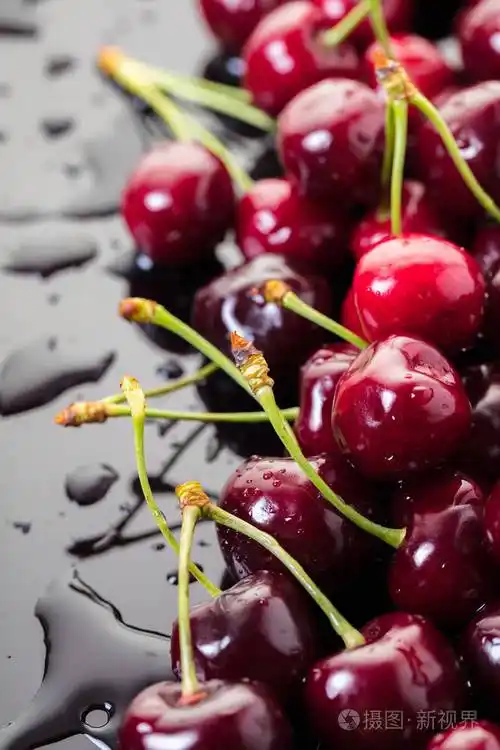 成熟的樱桃在黑色背景与水滴