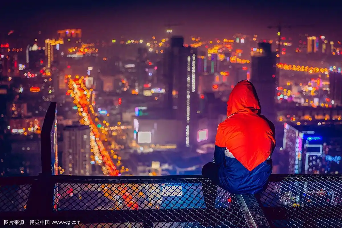 站在屋顶俯瞰城市夜景的人