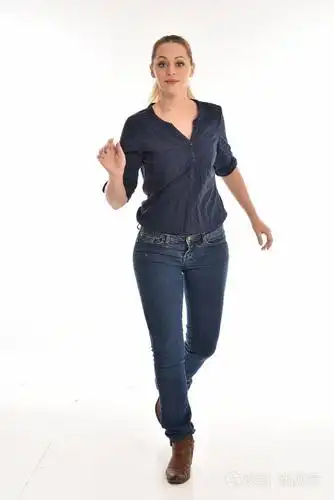 穿着简单的蓝色衬衫和牛仔裤站立姿势的女孩的全长肖像.