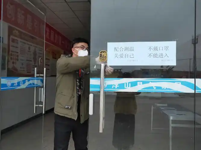 气象志愿者在大厅门口张贴醒目提示,"配合测温,关爱自己","不戴口