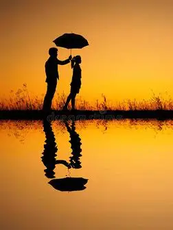 在情人的倒影中男女撑着雨伞在夕阳的映衬下