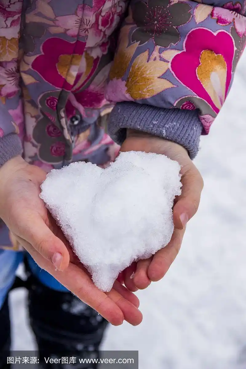 特写小女孩的手捧着一颗雪的心
