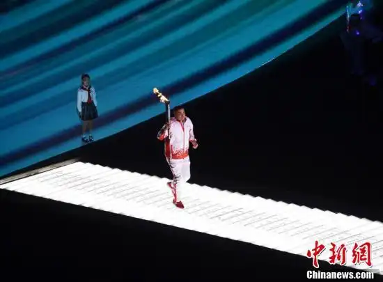 火炬手刘玉栋跑向火炬台.中新社记者 侯宇 摄