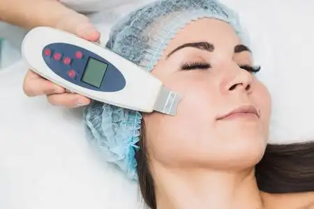 美容师在美容院为一名年轻女子做超声波洗脸手术照片