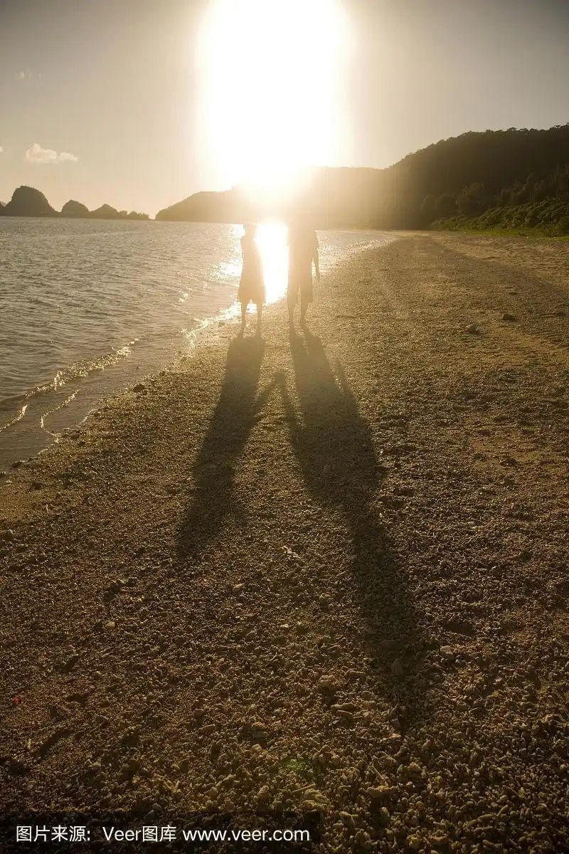 情侣们绑着双手在海滩上黄昏的剪影和影子