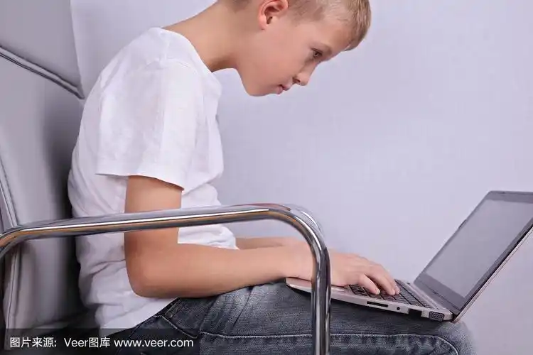 儿童不良不正确的坐姿.男孩在用笔记本电脑