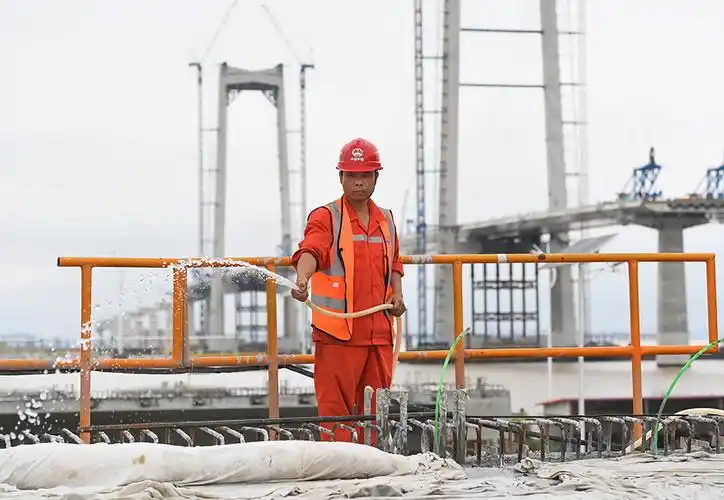 5月15日,工人对浇筑完成的深中通道第100片60米混凝土箱梁进行养护.