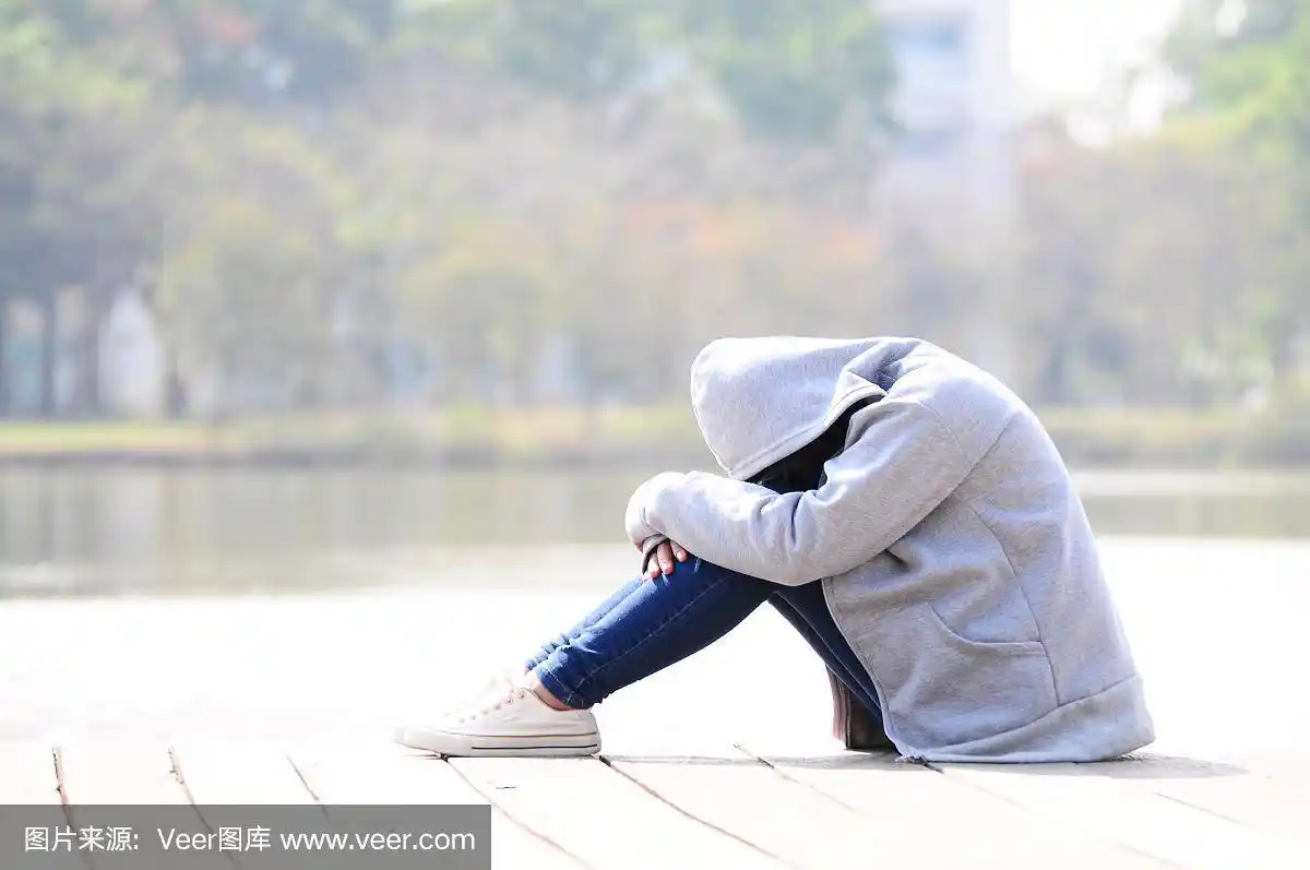 悲伤的女人抱着膝盖坐在河边