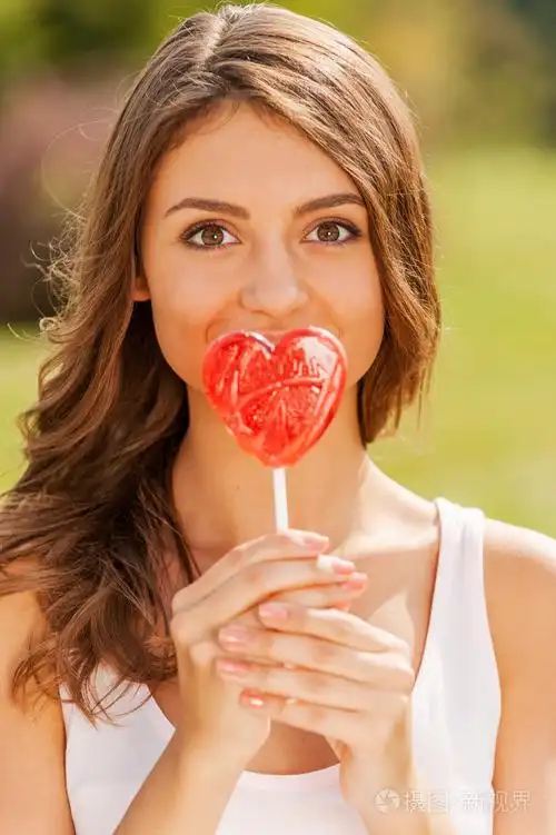 女人拿着棒棒糖在她的嘴唇