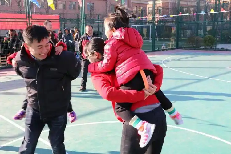 孩子们带着爸爸妈妈在操场上,参与着形式多样,内容有趣的亲子游戏.