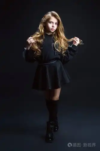 一个可爱的情感女孩在工作室的黑色背景上摆姿势的完整长度肖像.