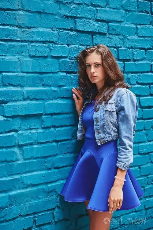 美丽的年轻女子,穿着蓝色衣服上青砖壁背景