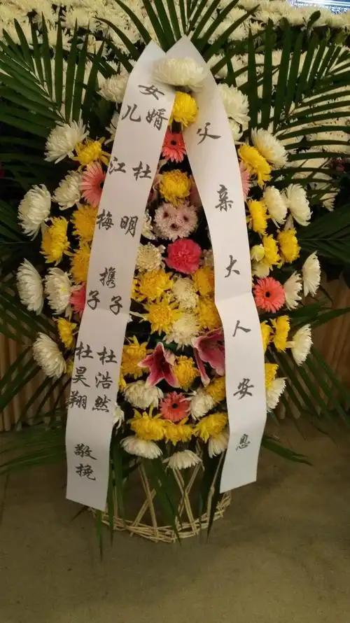 女儿江梅,女婿杜明及家人送的花圈紧挨中央花圈一侧.