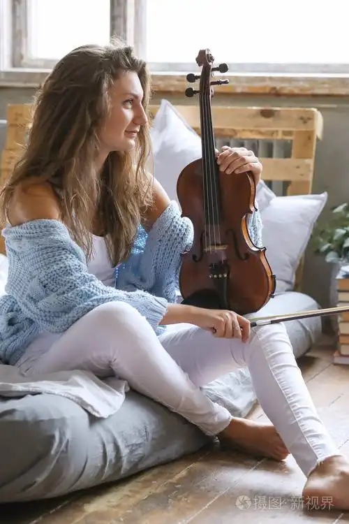 有魅力的年轻女子坐在床上拉小提琴摆姿势照片-正版商用图片0o3hf2-摄