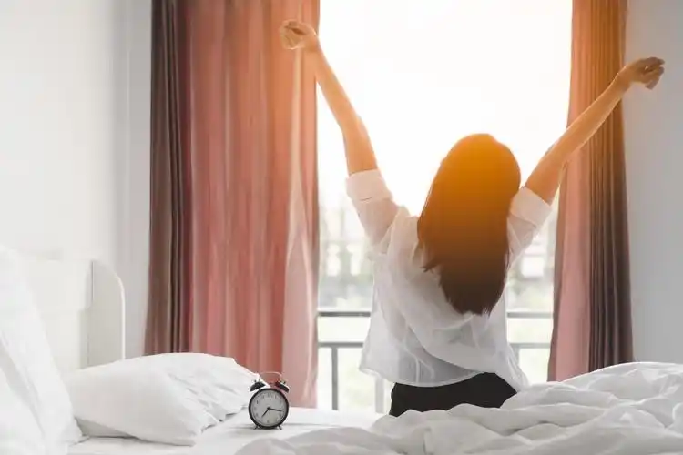 快乐的亚洲妇女在床上起床