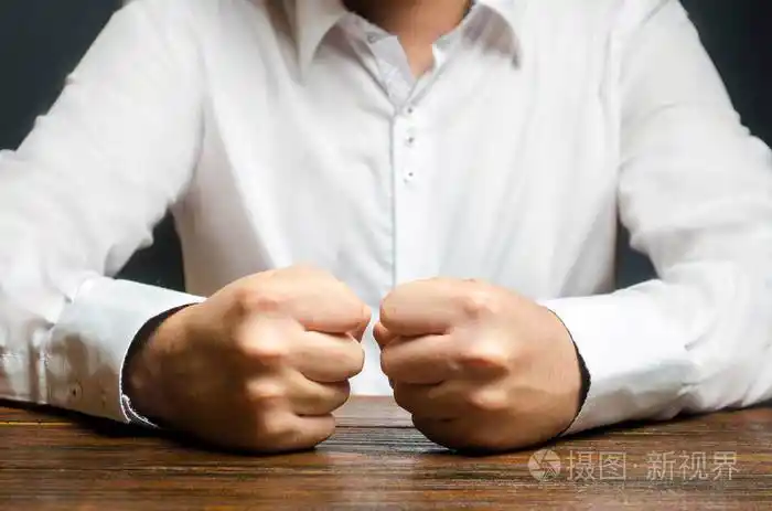 一个男人把紧握的拳头放在桌子上.忍耐的终结.这是无法忍受的.