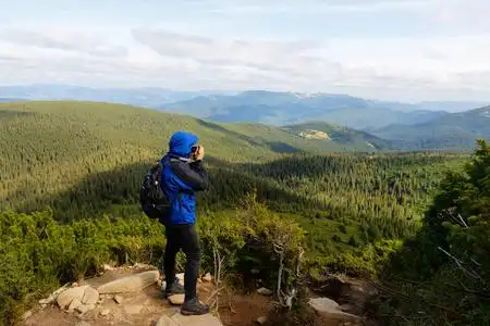 徒步旅行者站在山顶的岩石上拍照照片