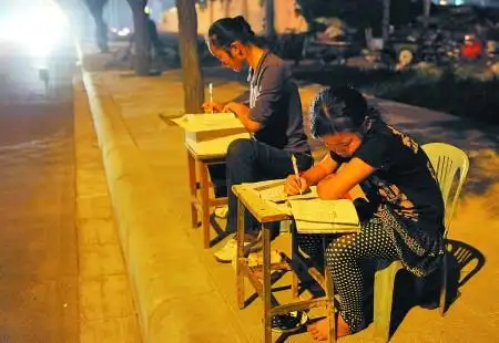 就会看到一对年幼的小姐妹在昏黄的路灯下,趴在凳子上写作业……怀着